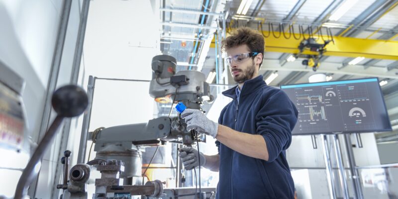 Robotics engineer fitting sensors to traditional engineering lathe in robotics research facility